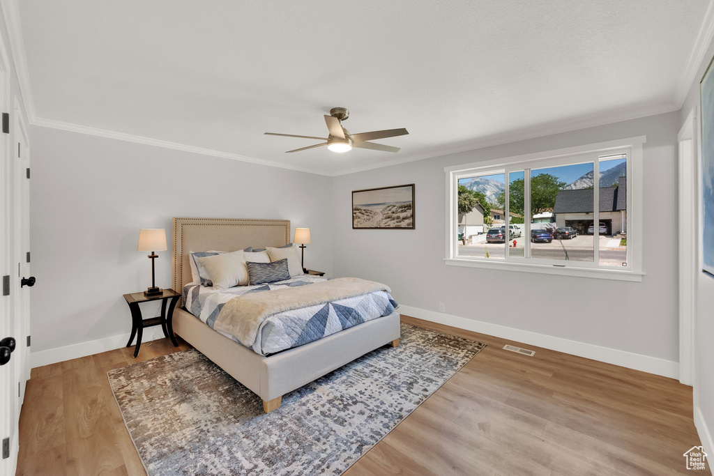 Bedroom with crown molding, light wood-style floors, and ceiling fan