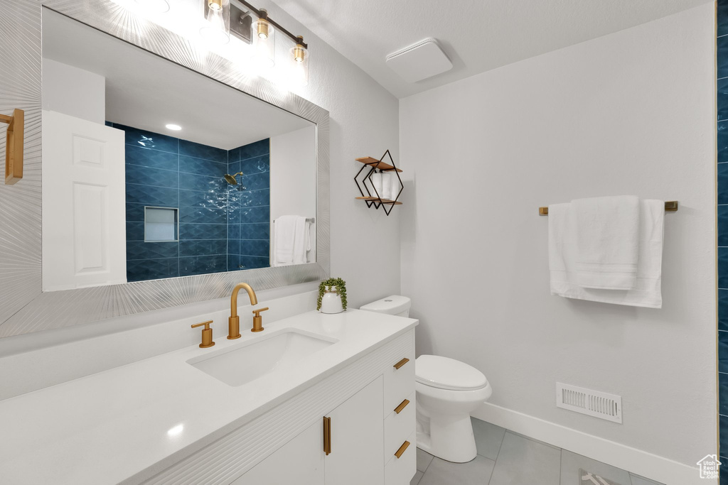 Full bath with tile patterned flooring, vanity, and tiled shower