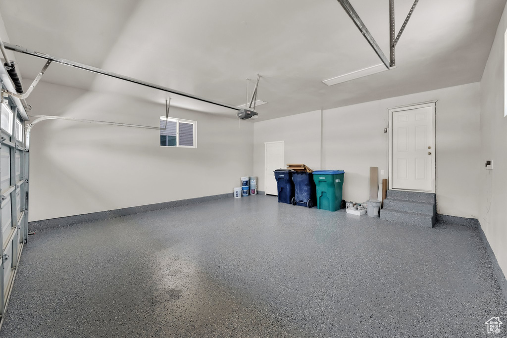 Garage featuring a garage door opener and baseboards
