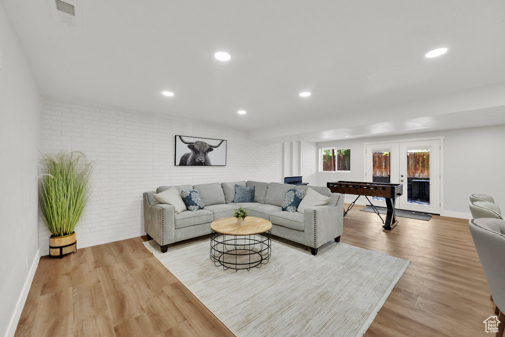 Living area with light wood finished floors, recessed lighting, and brick wall