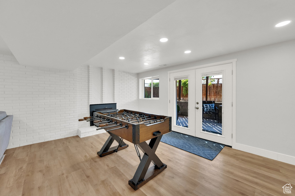 Game room featuring wood finished floors, brick wall, recessed lighting, and french doors