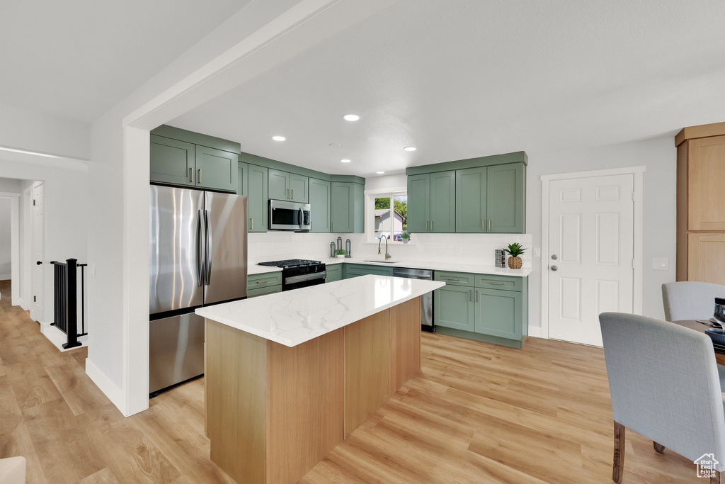 Kitchen with green cabinets, stainless steel appliances, light wood-type flooring, tasteful backsplash, and recessed lighting
