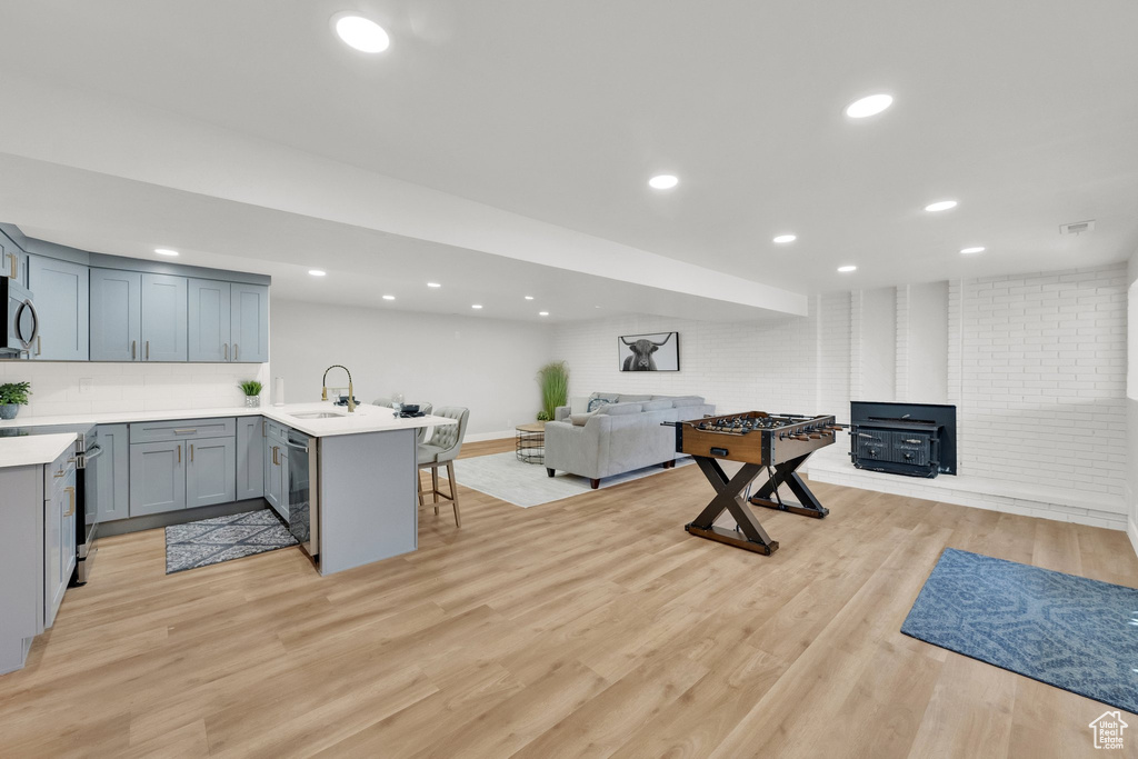 Kitchen featuring open floor plan, appliances with stainless steel finishes, a peninsula, a breakfast bar, and light countertops