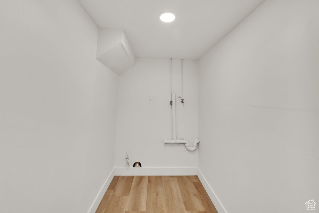 Laundry area with baseboards and light wood-style floors