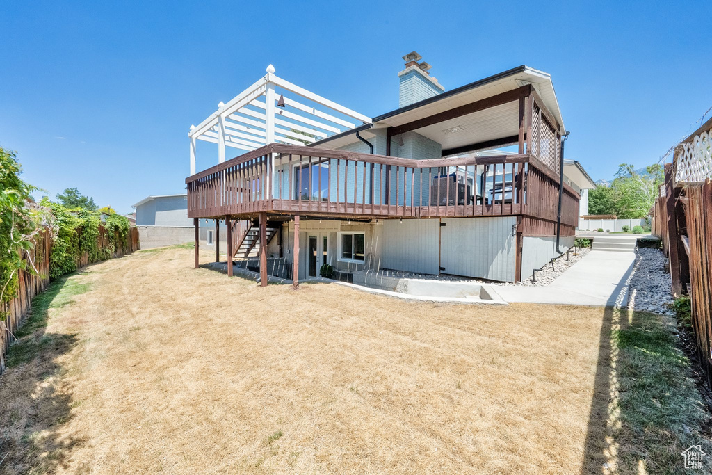 Back of property with a deck, stairway, a fenced backyard, and a chimney