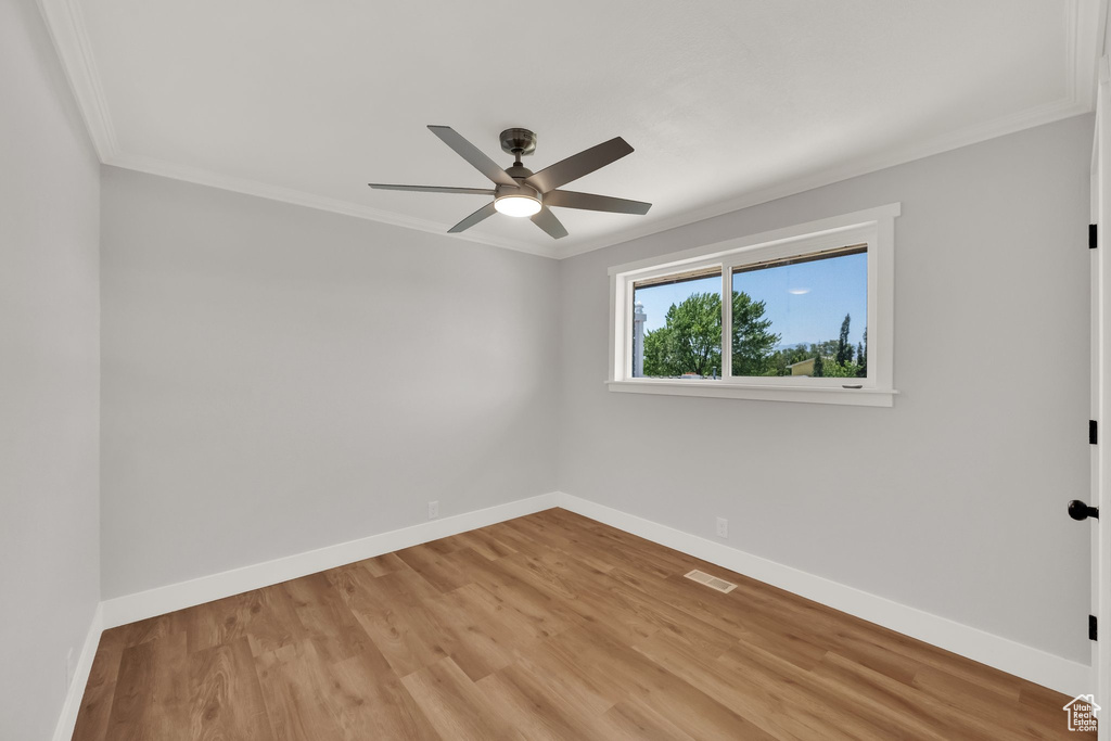 Empty room with crown molding, a ceiling fan, and light wood-style floors
