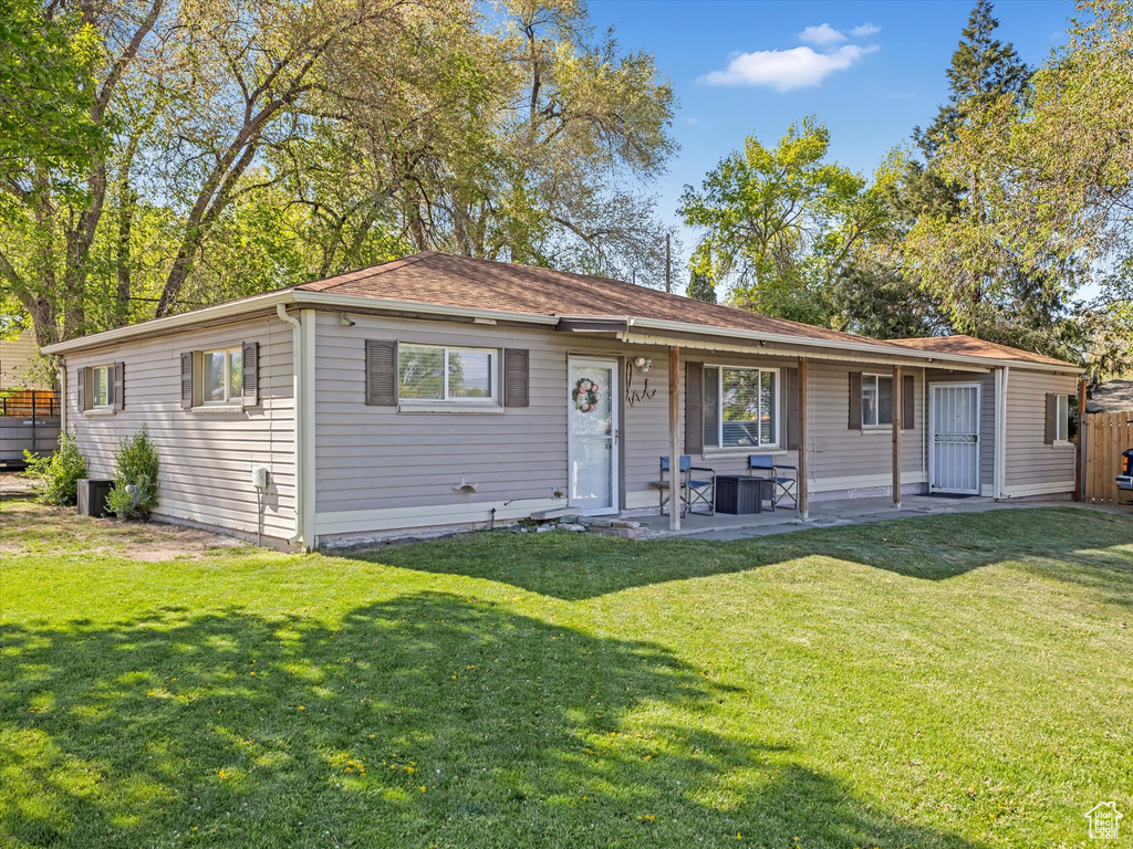 View of front of property with a front lawn, a patio, and roof with shingles