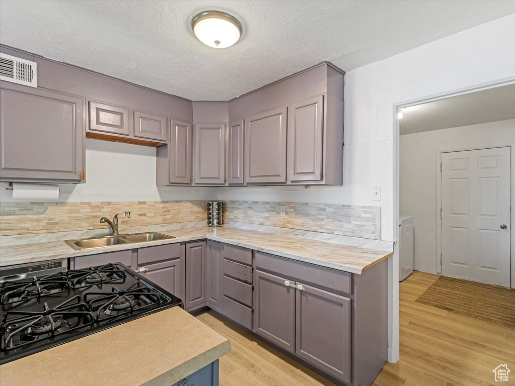 Kitchen featuring gray cabinetry, light countertops, decorative backsplash, gas range, and a textured ceiling