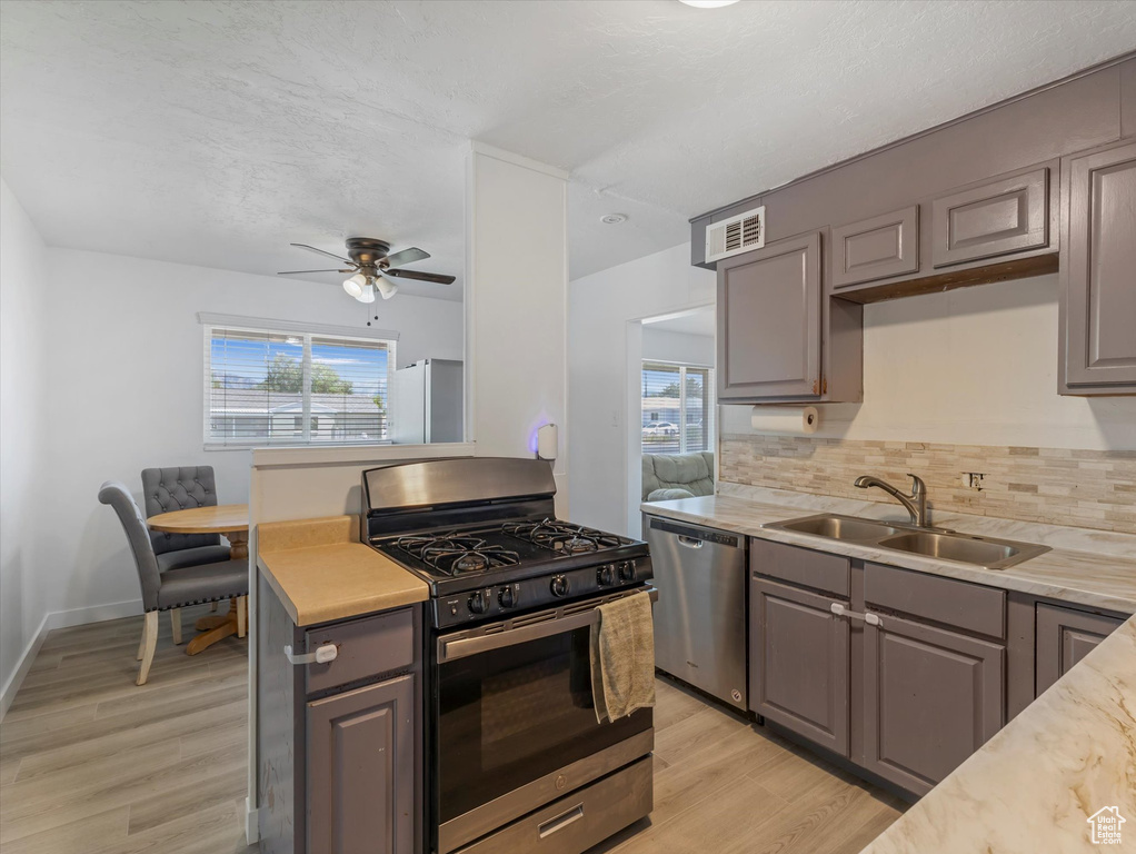 Kitchen with appliances with stainless steel finishes, gray cabinetry, healthy amount of natural light, and decorative backsplash