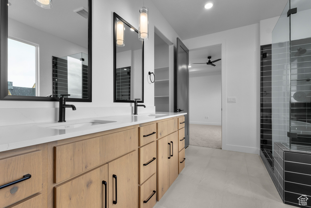Full bathroom featuring double vanity, a ceiling fan, and a tile shower