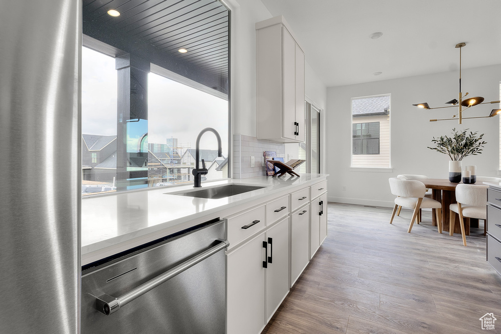 Kitchen featuring stainless steel dishwasher, light wood finished floors, light countertops, white cabinetry, and recessed lighting