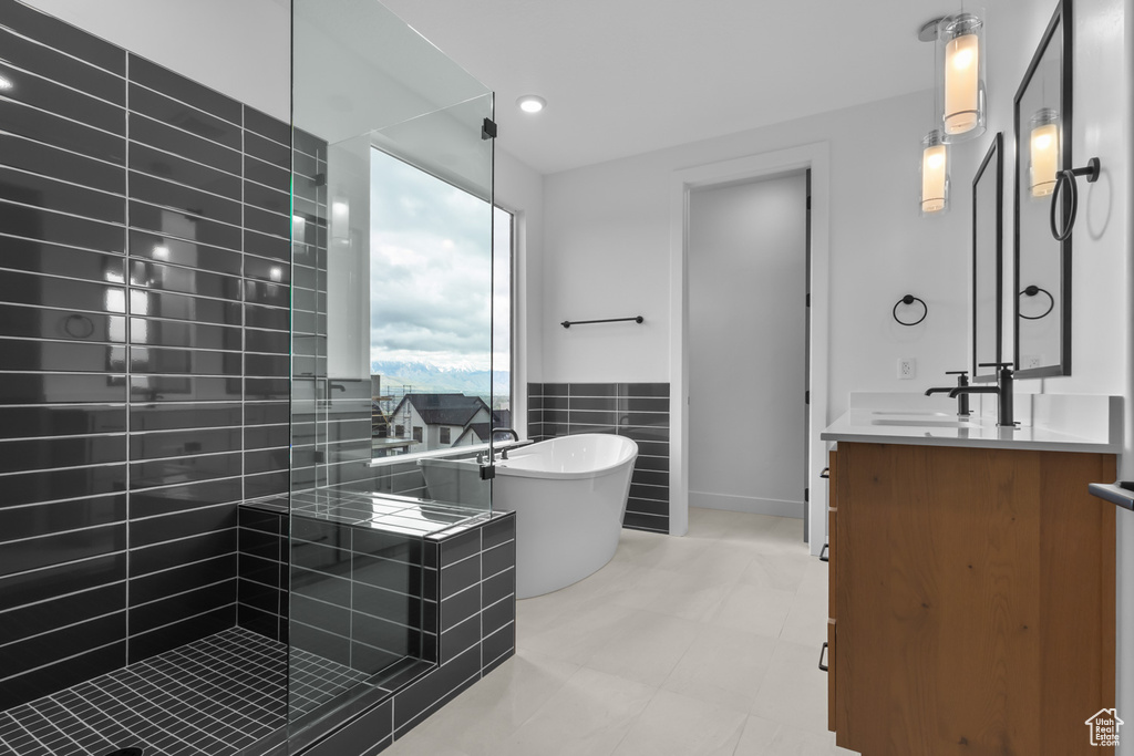 Full bathroom featuring vanity, a freestanding tub, tiled shower, and a wainscoted wall