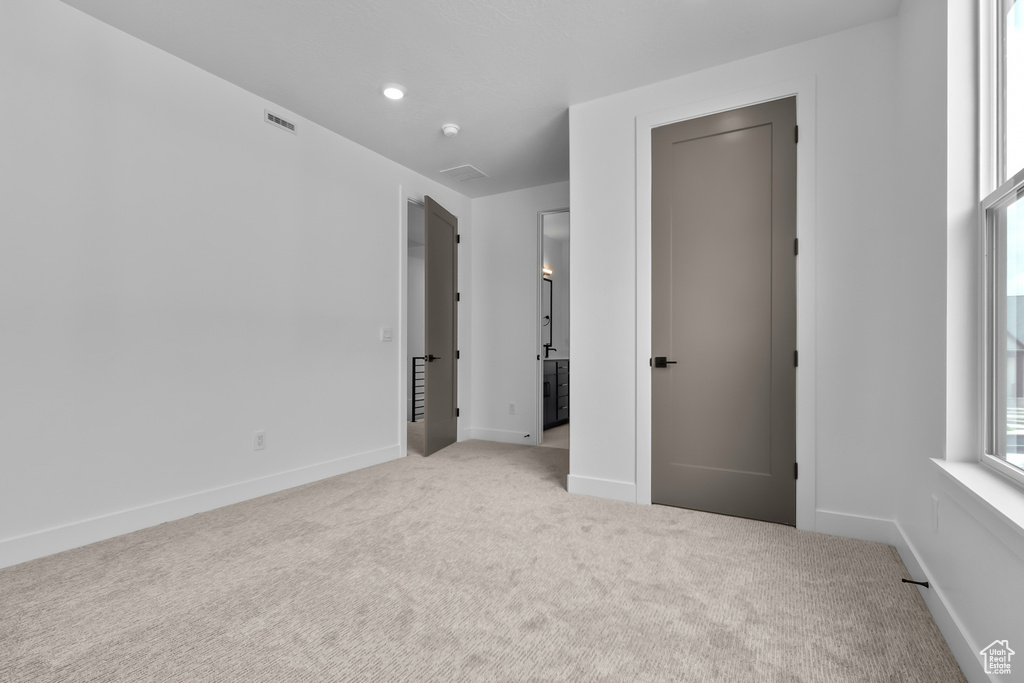 Unfurnished bedroom featuring light carpet and baseboards