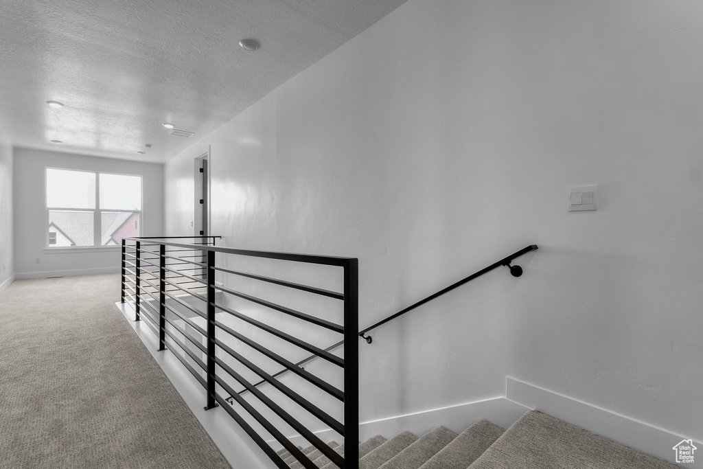 Stairs featuring carpet and a textured ceiling