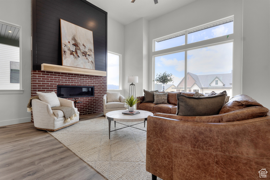 Living room featuring wood finished floors, a fireplace, and ceiling fan