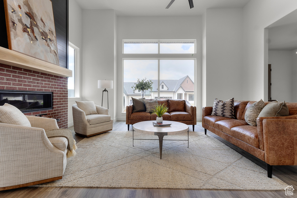 Living area with a ceiling fan, a fireplace, and wood finished floors