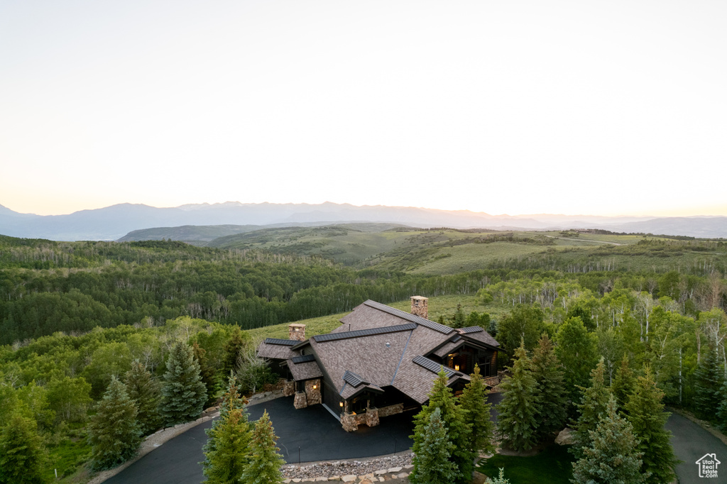 Aerial view of property and surrounding area featuring a heavily wooded area and a mountain backdrop