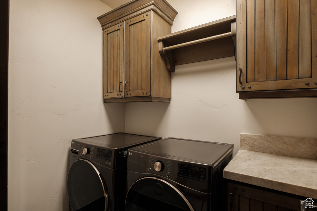 Washroom with cabinet space and washing machine and clothes dryer