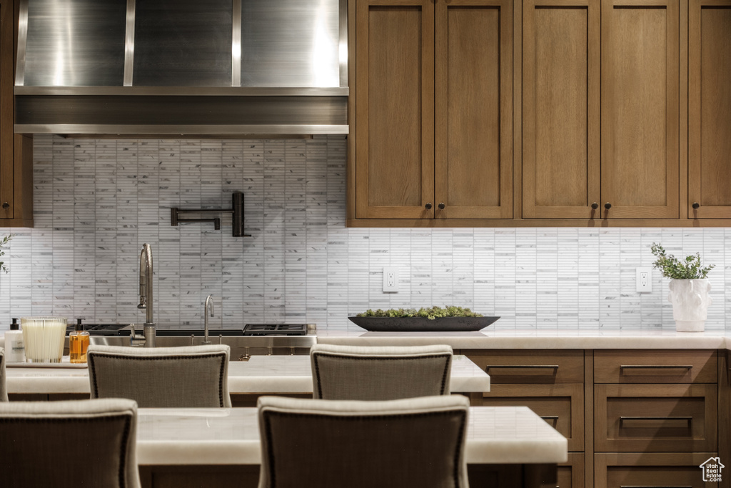 Kitchen with decorative backsplash, light countertops, and brown cabinetry
