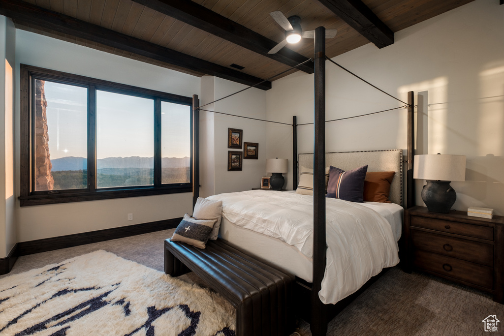 Carpeted bedroom featuring a wooden ceiling with exposed beams