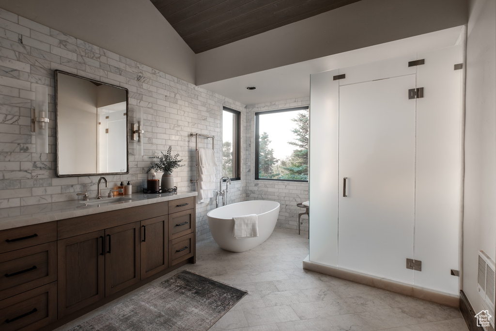 Bathroom featuring vanity, a soaking tub, vaulted ceiling, wooden ceiling, and tile walls