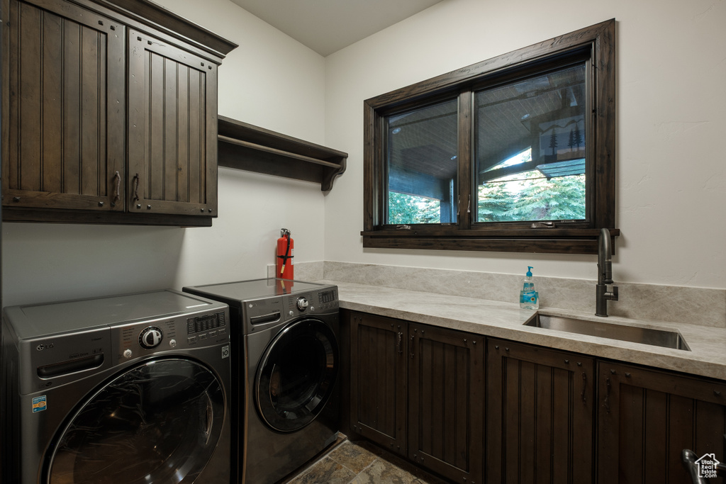 Laundry area featuring cabinet space, washer and dryer, and stone finish floors
