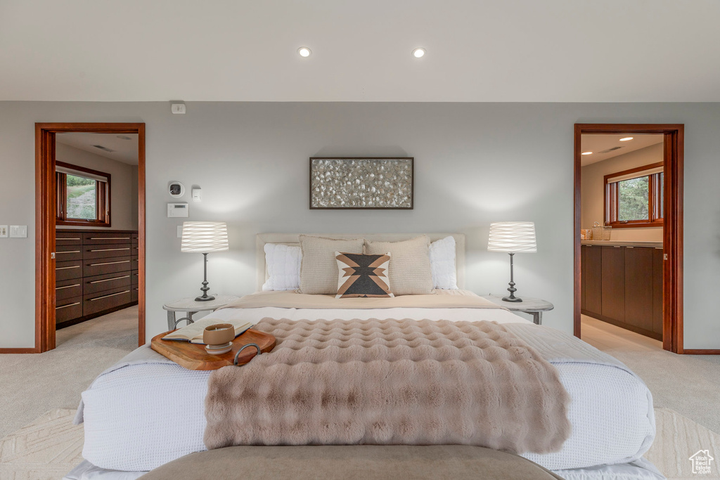 Bedroom featuring light carpet, recessed lighting, multiple windows, and ensuite bathroom