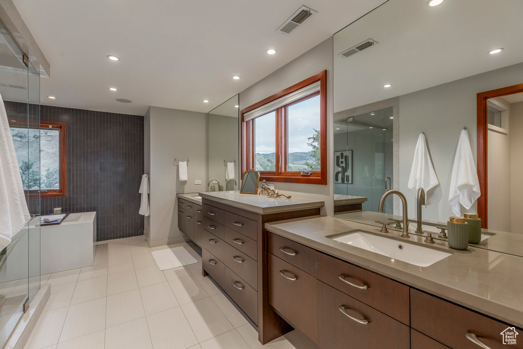 Full bathroom featuring a stall shower, two vanities, a freestanding bath, recessed lighting, and tile patterned floors