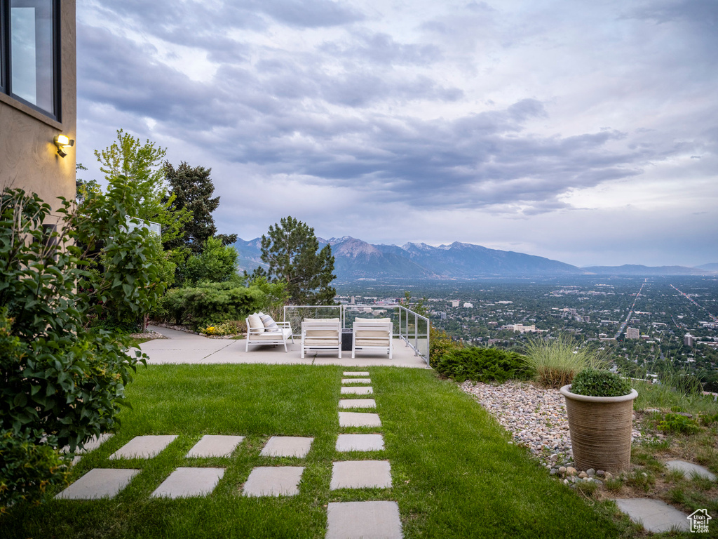 View of grassy yard featuring a mountain view and a patio