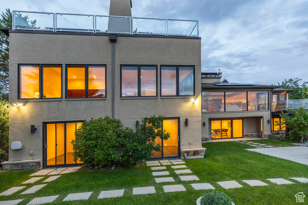 Back of property with a yard, a balcony, and stucco siding