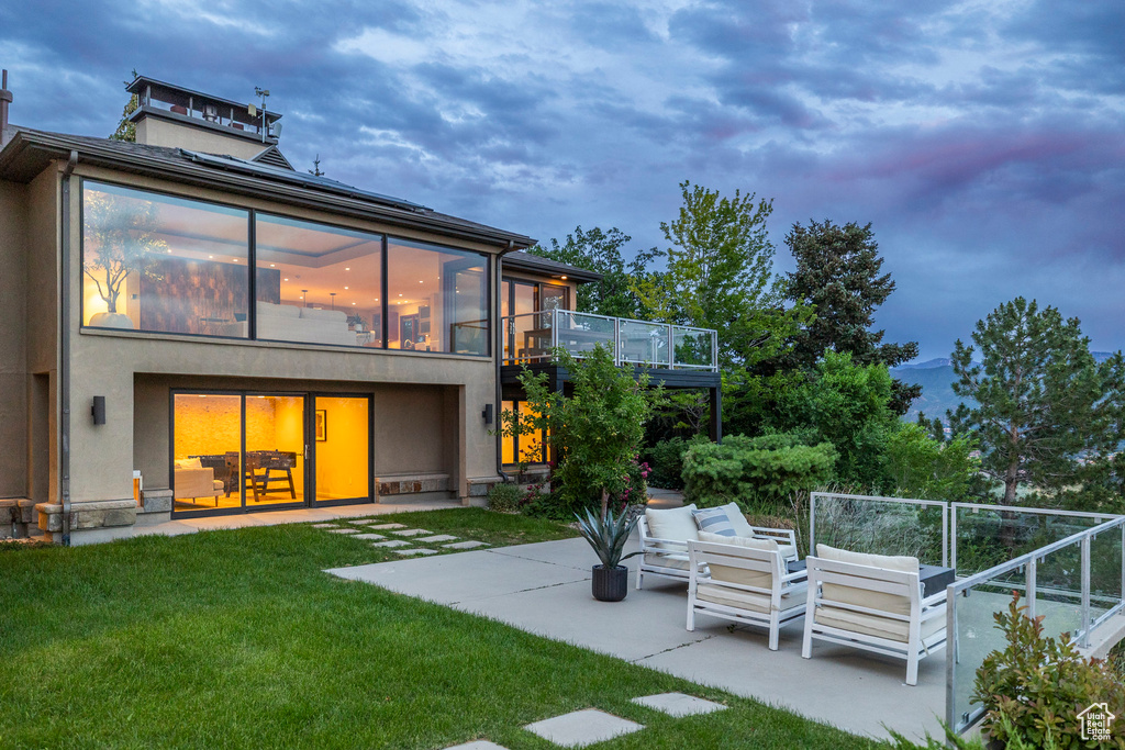 Back of property featuring a patio, a lawn, and an outdoor living space