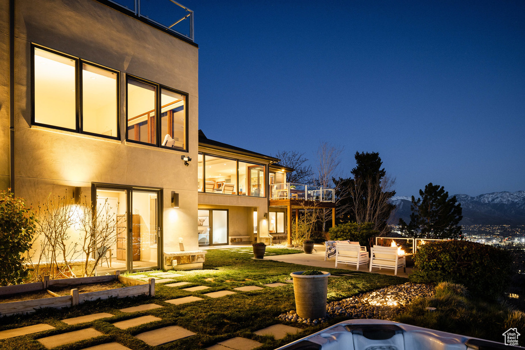 Back of house at twilight featuring a patio area, stucco siding, and a deck