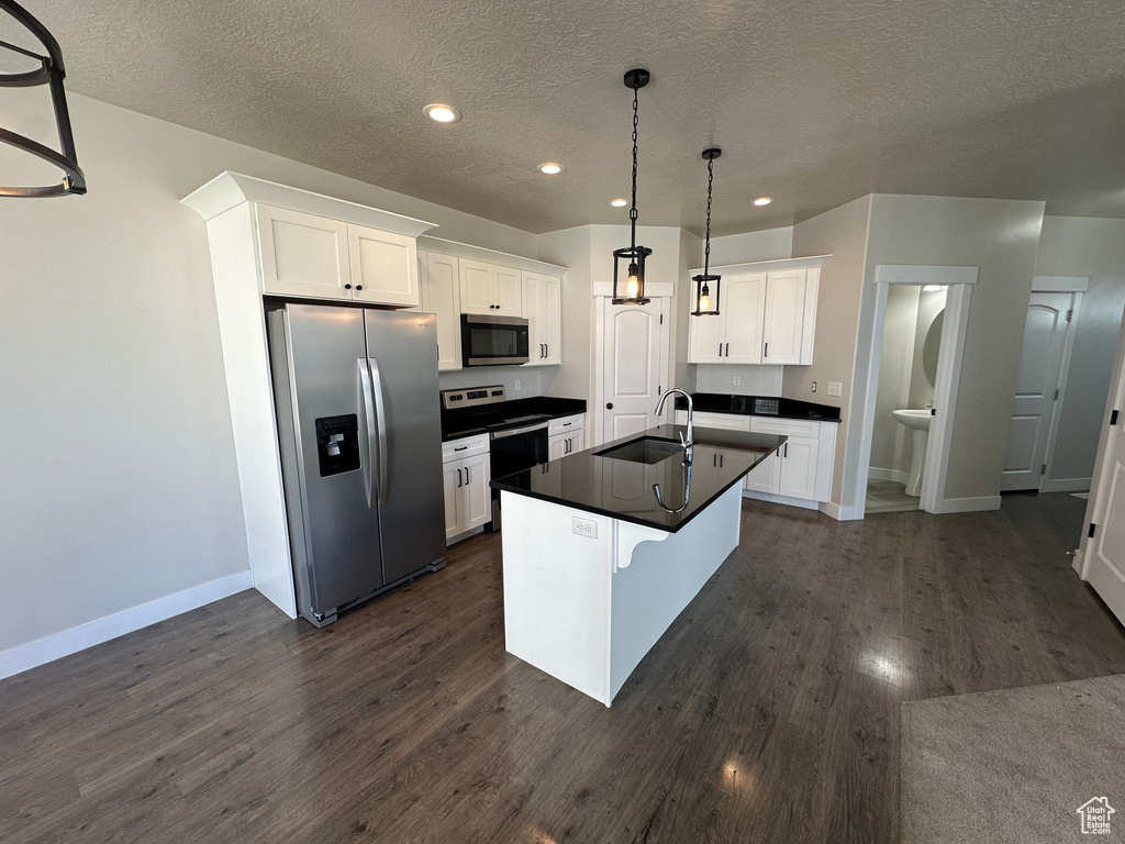 Kitchen with appliances with stainless steel finishes, dark countertops, a textured ceiling, recessed lighting, and white cabinets