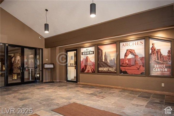 Cinema featuring stone finish floors, high vaulted ceiling, and french doors
