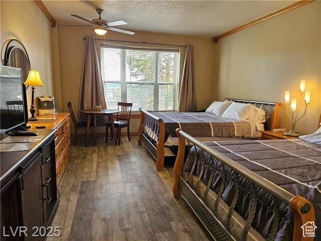 Bedroom featuring dark wood-type flooring, crown molding, and a textured ceiling