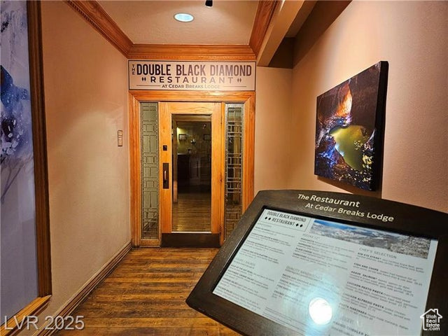 Hall with ornamental molding and dark wood-style flooring