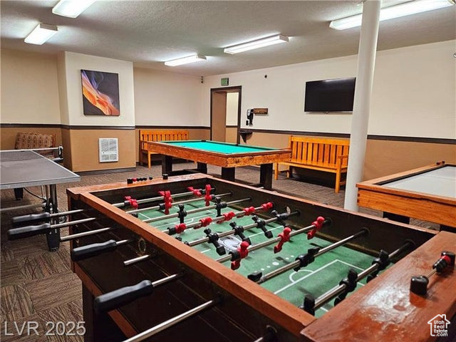Recreation room featuring carpet flooring and a textured ceiling