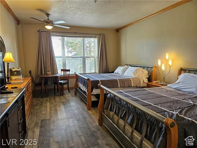Bedroom with ornamental molding, dark wood-style floors, and a textured ceiling