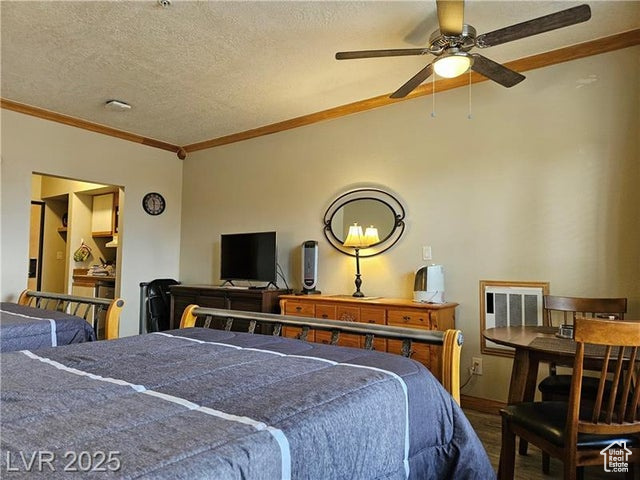 Bedroom with wood finished floors, ornamental molding, and a textured ceiling