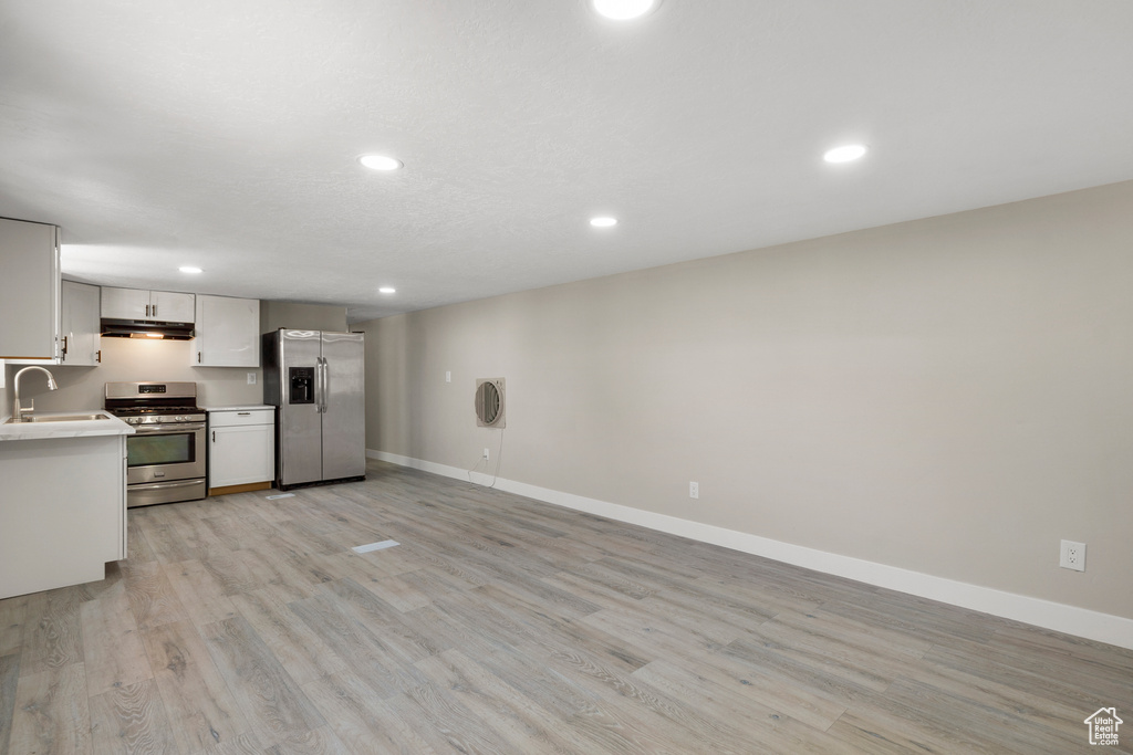 Kitchen with appliances with stainless steel finishes, light countertops, light wood-type flooring, recessed lighting, and under cabinet range hood