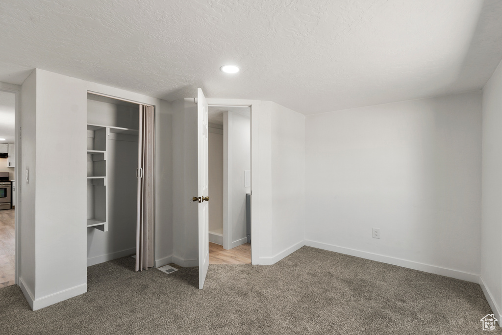 Unfurnished bedroom featuring carpet, a closet, a textured ceiling, and recessed lighting