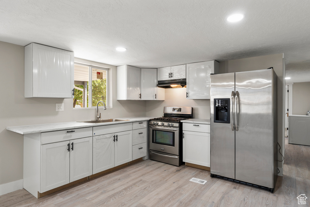 Kitchen featuring appliances with stainless steel finishes, under cabinet range hood, light wood-style floors, light countertops, and recessed lighting