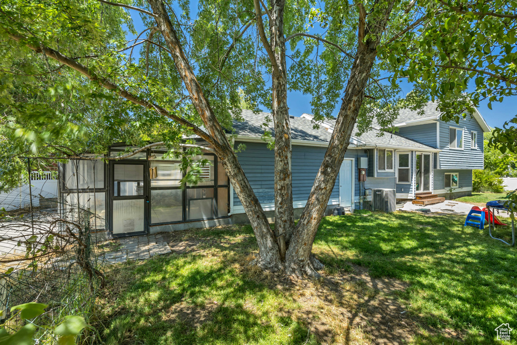 Back of property with entry steps, a lawn, and roof with shingles