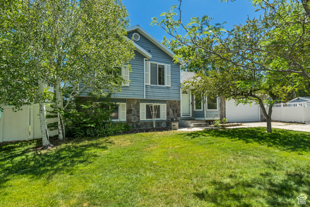 Split level home featuring stone siding, a garage, and driveway
