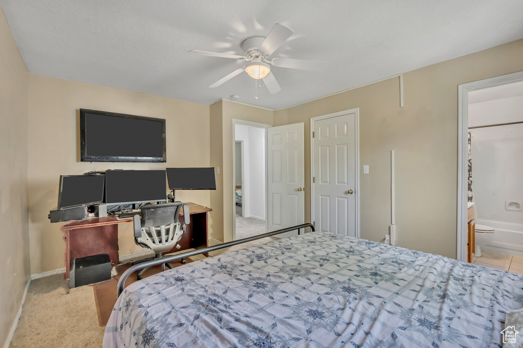 Carpeted bedroom with a ceiling fan, ensuite bathroom, and an office area