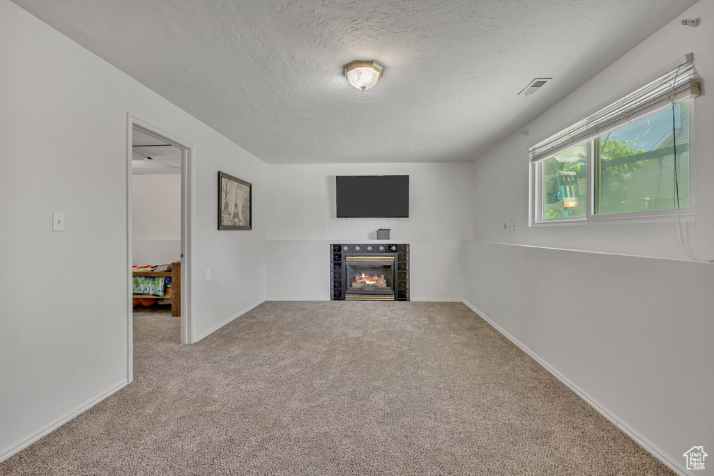 Unfurnished living room with a textured ceiling, carpet, and a fireplace