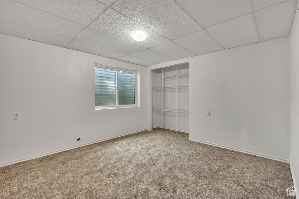 Unfurnished bedroom featuring carpet floors, a paneled ceiling, and a closet