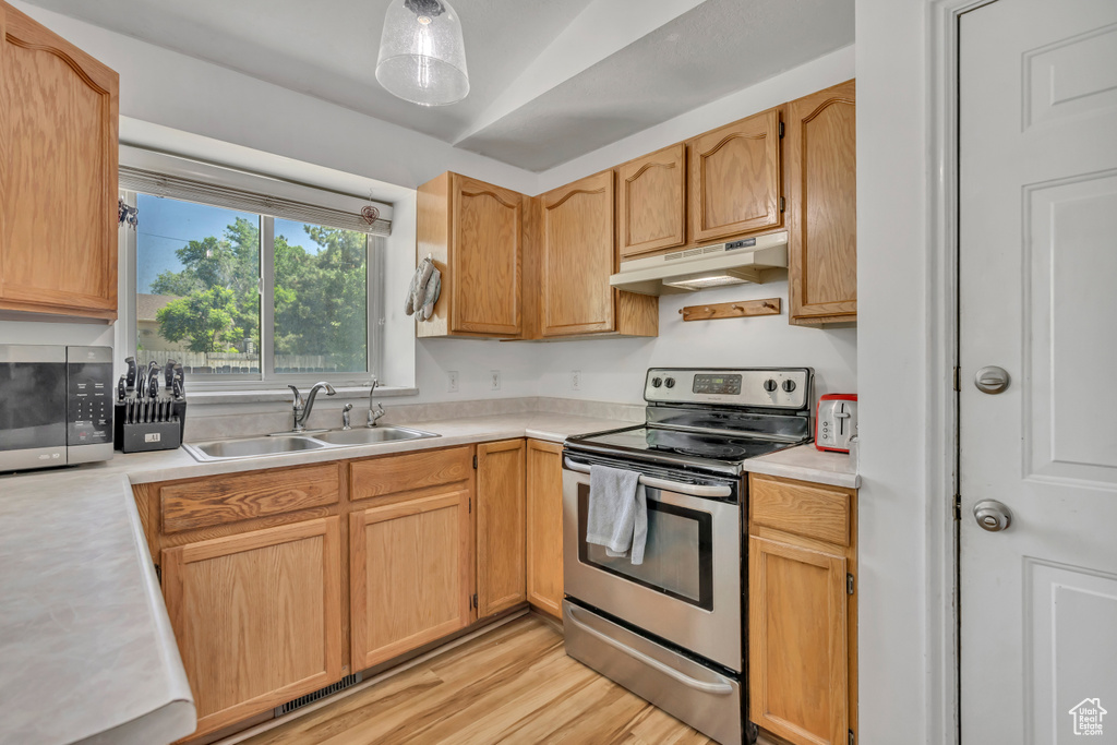 Kitchen with stainless steel appliances, under cabinet range hood, light countertops, and light wood-style floors