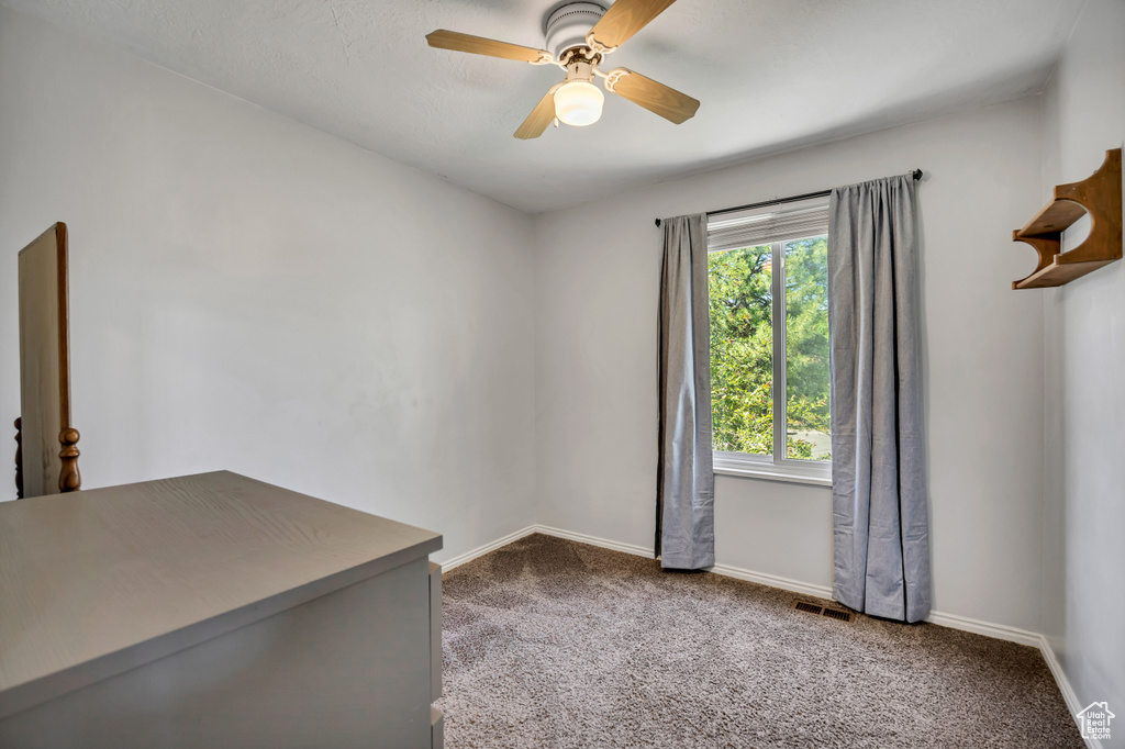Carpeted spare room with ceiling fan and baseboards