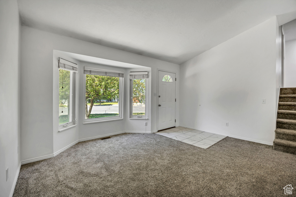 Carpeted foyer entrance with stairway and tile patterned flooring